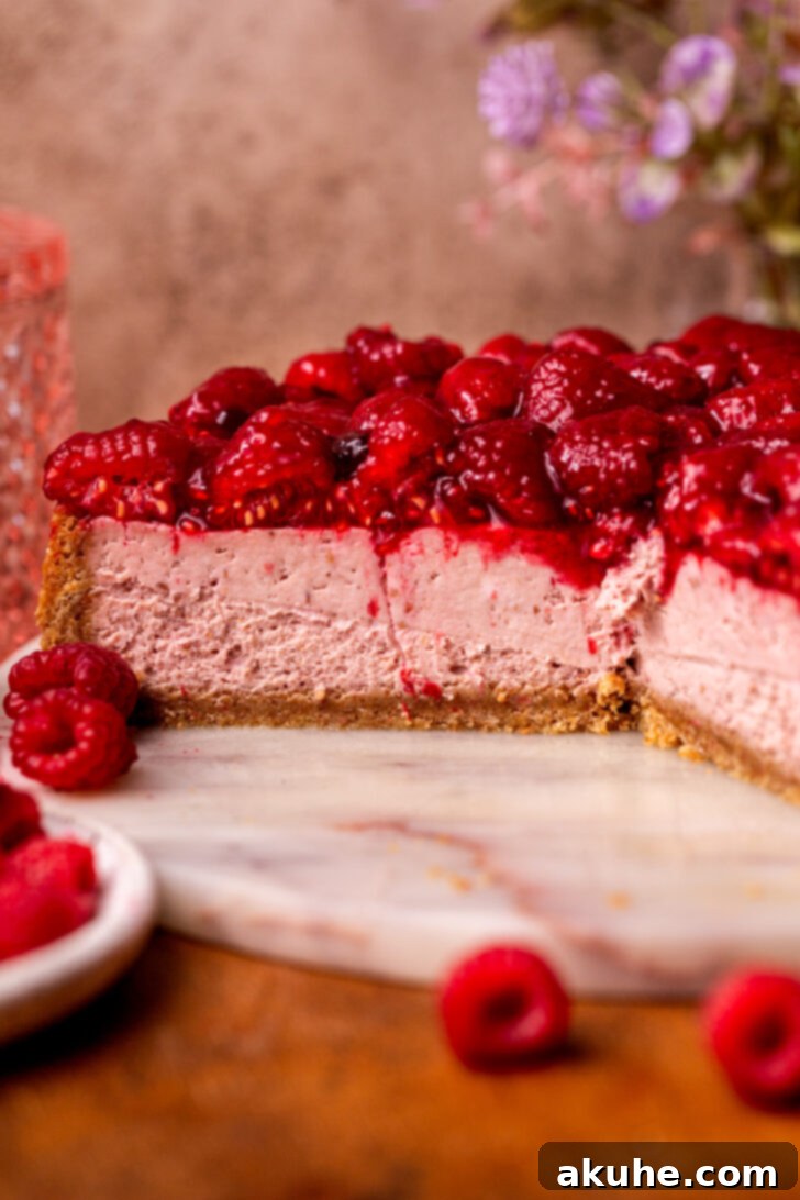 A stunning side view of the raspberry cheesecake, highlighting the layers of graham cracker crust, creamy cheesecake, and luscious raspberry topping.