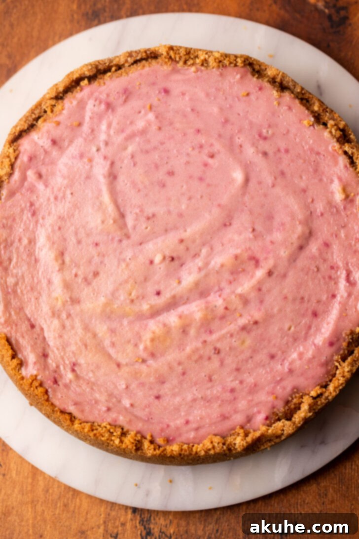 The baked cheesecake, cooled and ready for the raspberry topping, sitting on a platter.